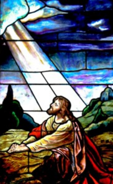 Stained glass image of Jesus looking towards the sky, light beaming down.